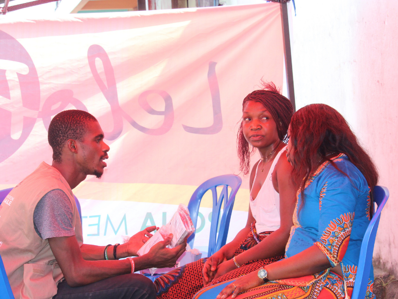 Group of three people inside tent at family planning marketplace.