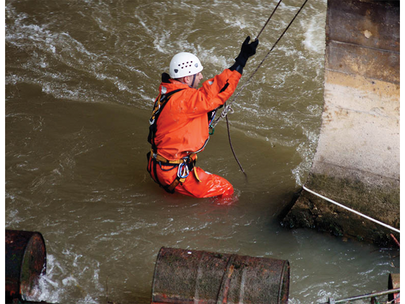 Person lowering themselves into rushing water wearing a safety harness
