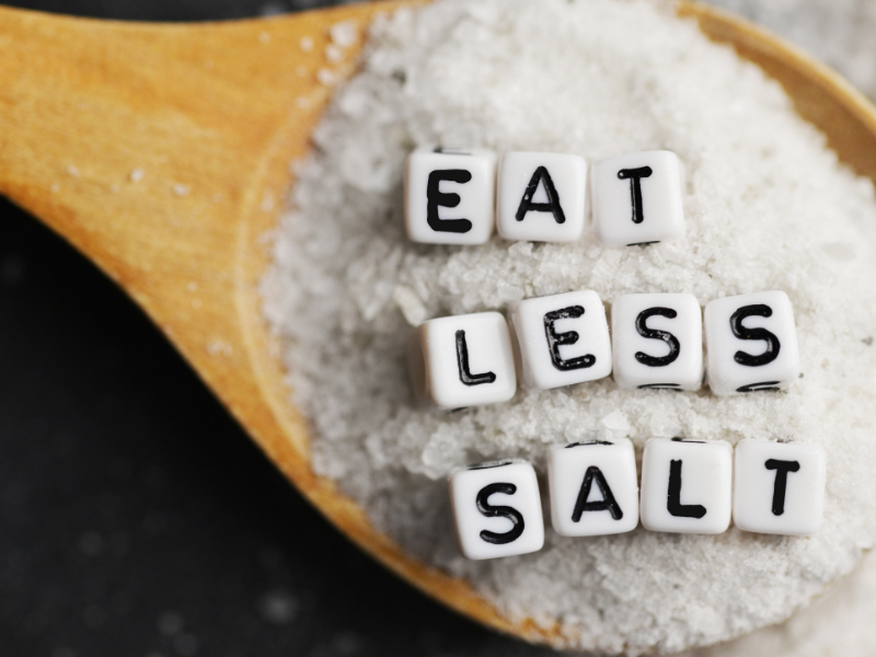 A spoon of salt with letters spelling out "eat less salt"