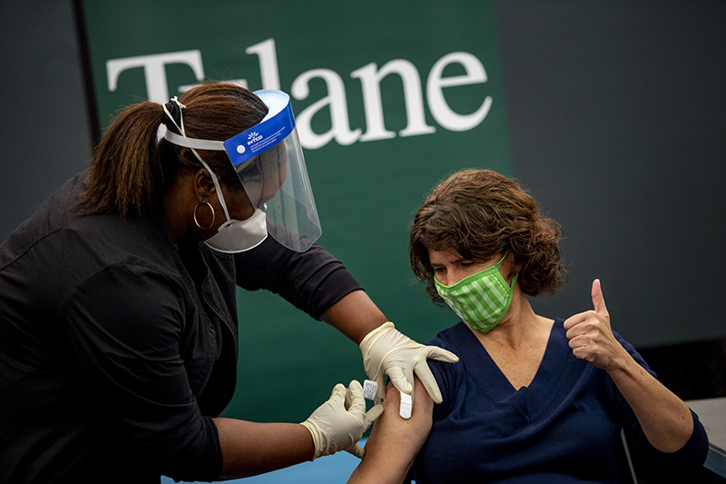 Photo of Tulane School of Medicine researcher Lisa Morici (on right) watches as she receives a dose of the Pfizer/BioNTech COVID-19 vaccine from Sharjanae Crosby (on left)