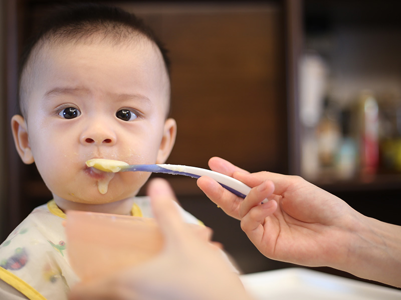 Infant eating a jar of baby food