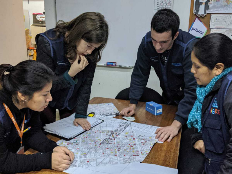 Bianca Delgado with Asociatión Benéfica PRISMA, Jessica Brewer, a student when the study was conducted, and Raphael Duran and Nelly Briceno with Asociatión Benéfica PRISMA review maps of Lima, Peru