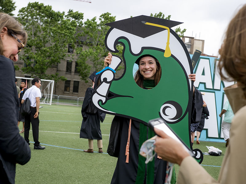 female student smiling with her face in the hole of a Tulane green wave cut out