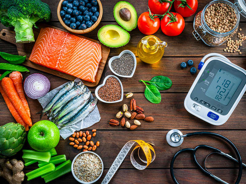 Vegetables, fish, fruits, arranged with stethoscope and BP monitor