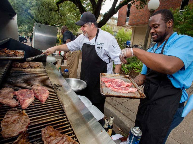 Two grillmasters cooking up steaks on an outdoor grill