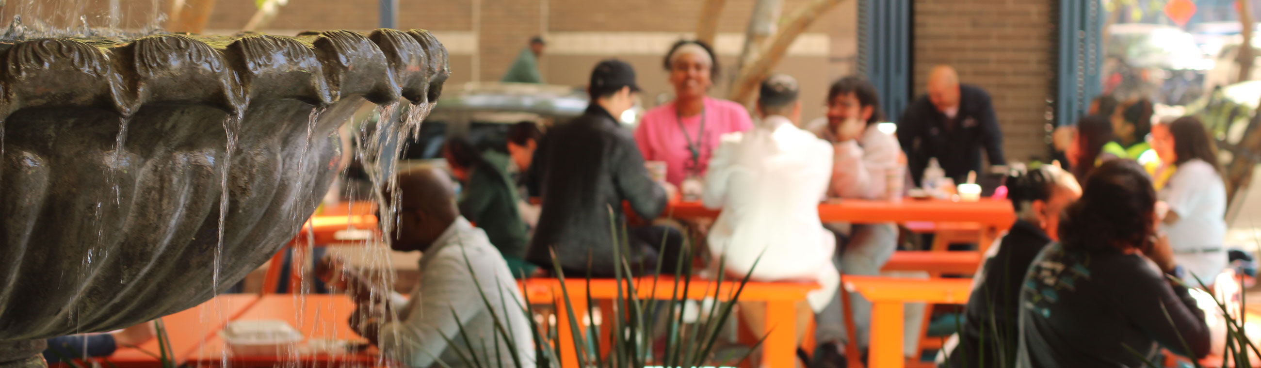 Fountain with people at a table in the background