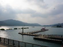 Nice view of a lake with long wooden docks, a boat, and distant mountains under a cloudy sky.