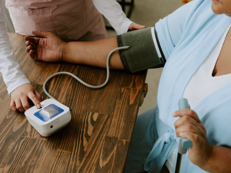 A woman having her blood pressure checked with a cuff on her arm.
