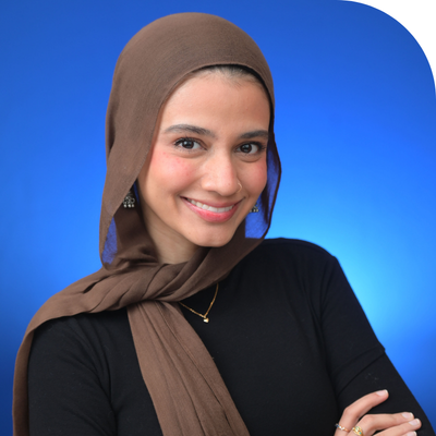 A young muslim lady in a black top with a brown scarf arounf her head and scarf smiling