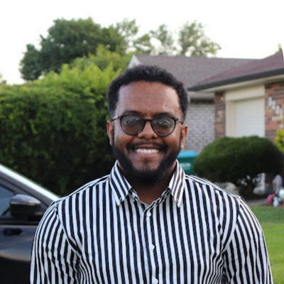 black young man in glasses smiling in a horizontal striped navy blue and white shirt