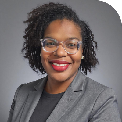 Smiling Black woman in clear glasses, red lipstick, and grey blazer.