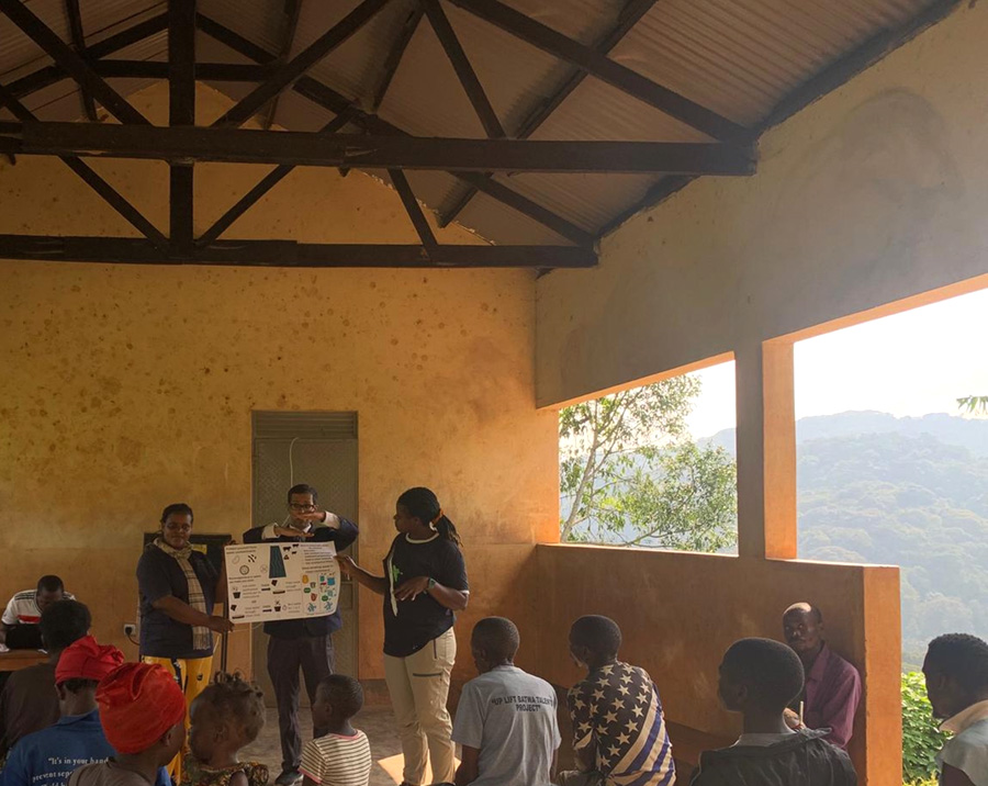 Photograph of a community meeting in an open-air building with a mountain view.