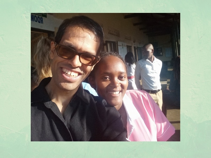 Photograph of a smiling man wearing glasses, standing next to a smiling woman in a pink shirt.