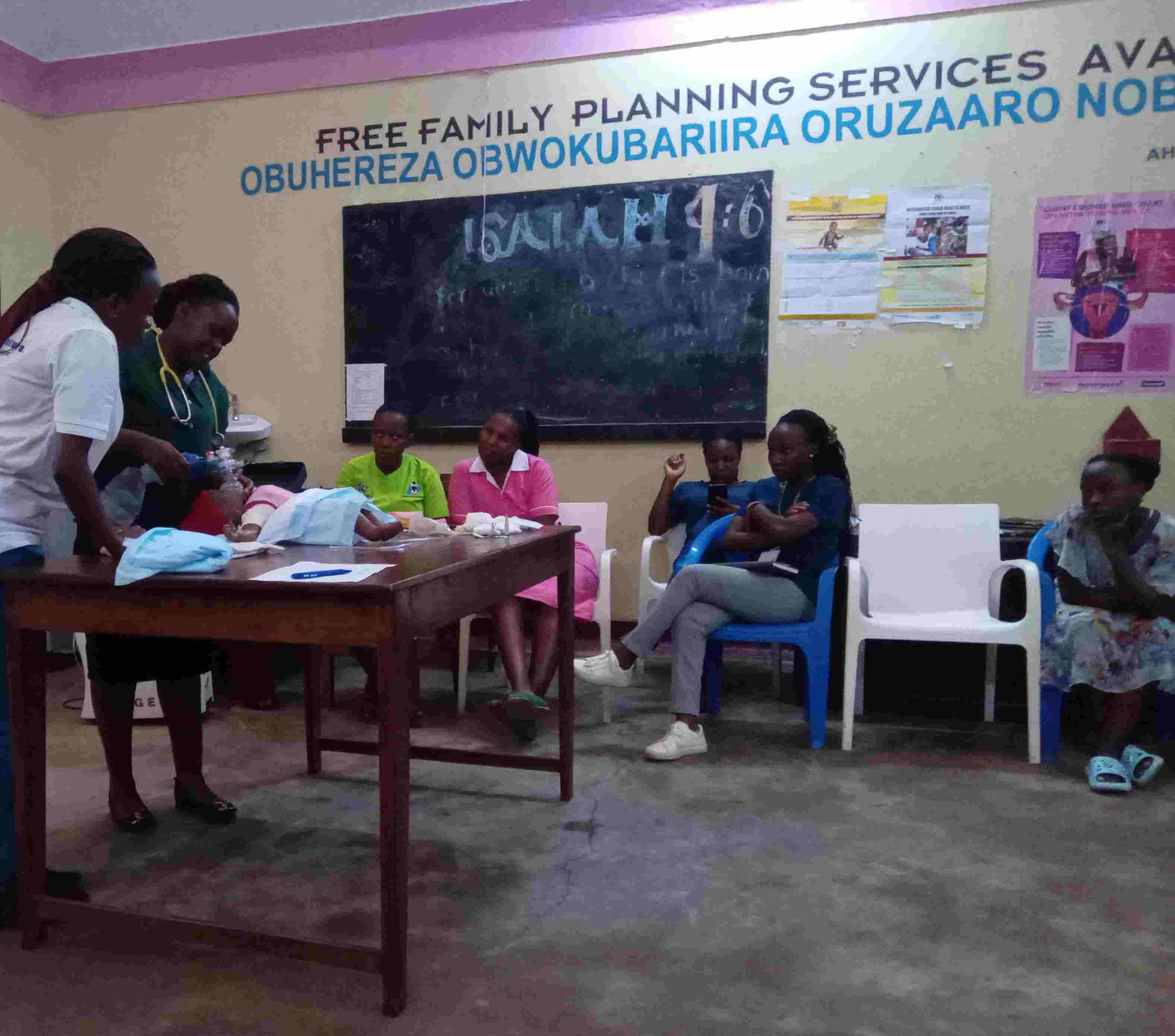 Photograph of healthcare workers assisting patients seated in a clinic.