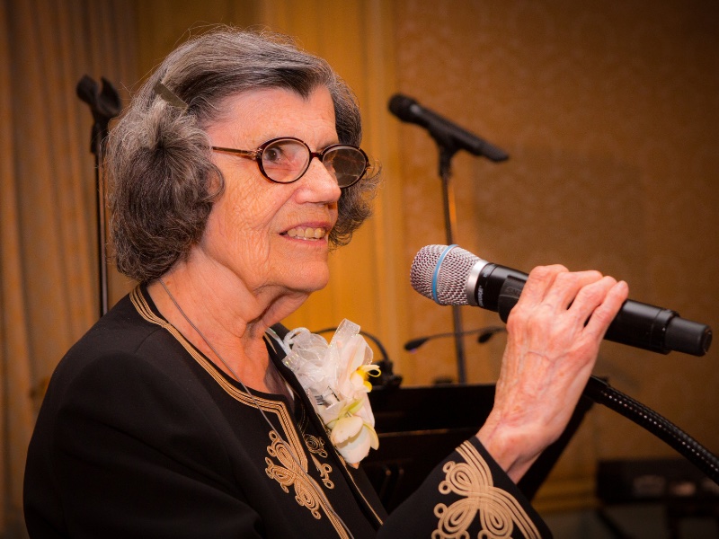 Dr. Ann Metzinger speaking into microphone at Centennial Gala