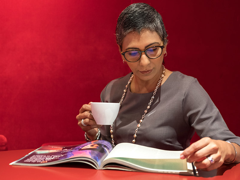 Person reads open book on table with cup