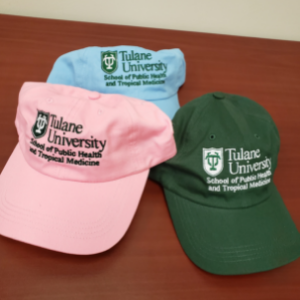 Image of Tulane SPHTM baseball caps: one in pink, one in blue, and one in green