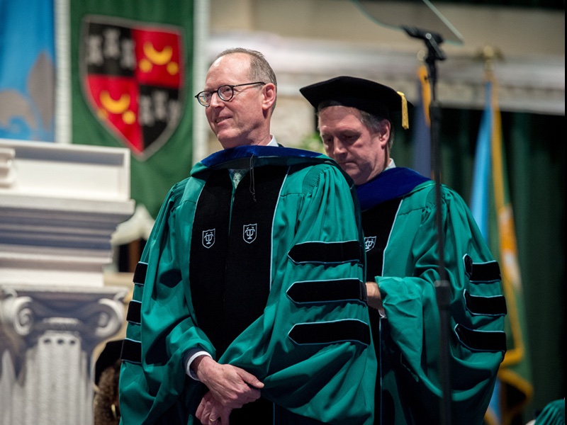 Paul Farmer in green doctoral robes getting hooded as a Doctor of Human Letters