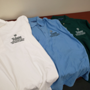 Image of Tulane SPHTM polo shirts: one in white, one in blue, and one in green