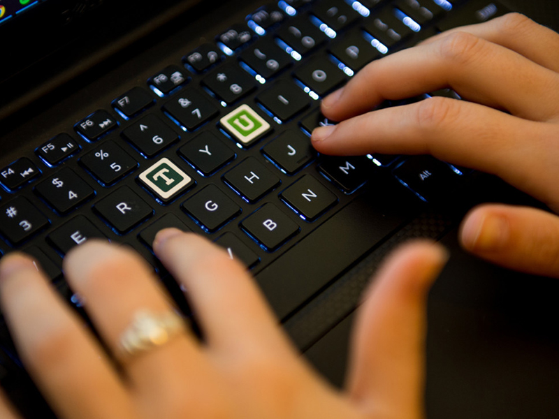 hands on a keyboard with a T and U highlighted in Tulane green colors and traditional typeface