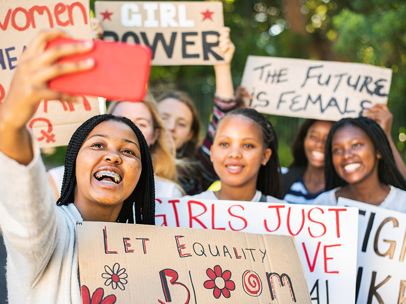 Young women with "future is female" signs, education bloom, taking a selfie in a group