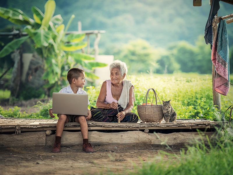 Child with computer and grandmother in a rural setting