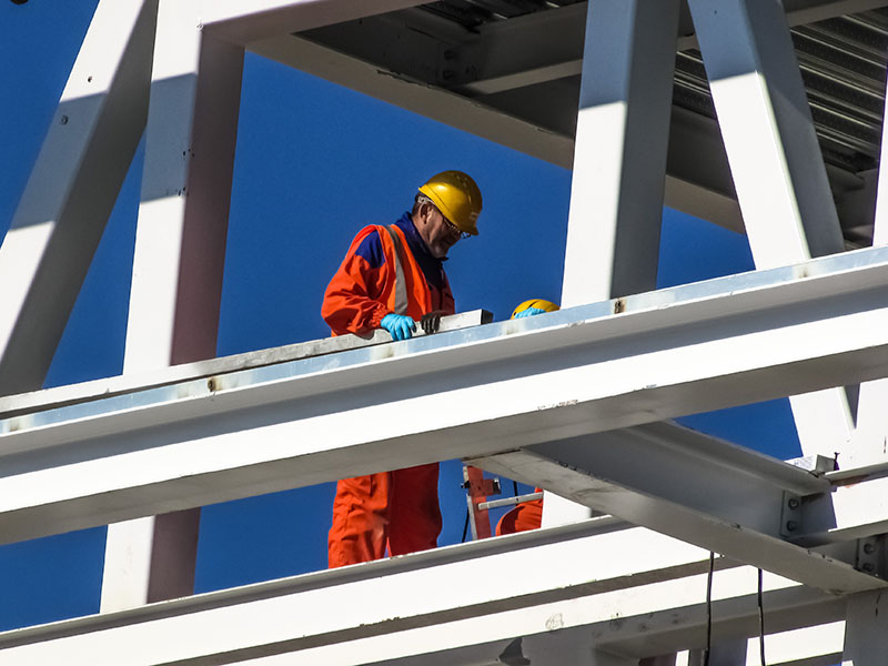 Worker in safety gear on steel beams.