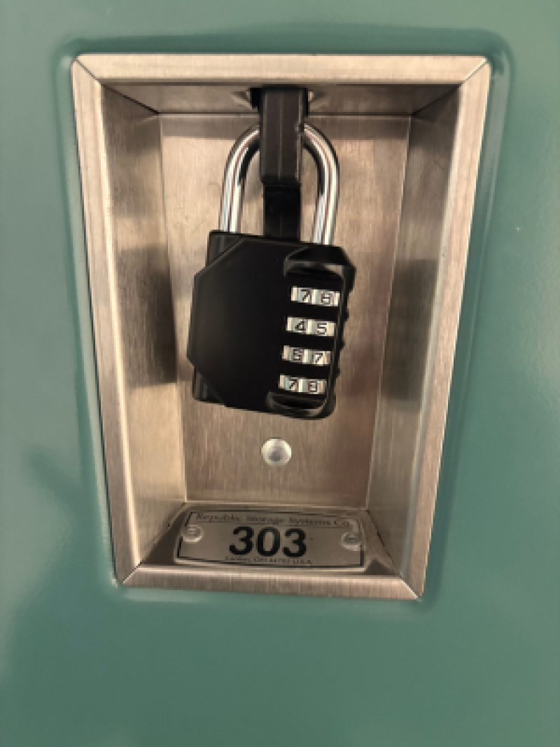 Black combination padlock on a metal panel labeled 303.