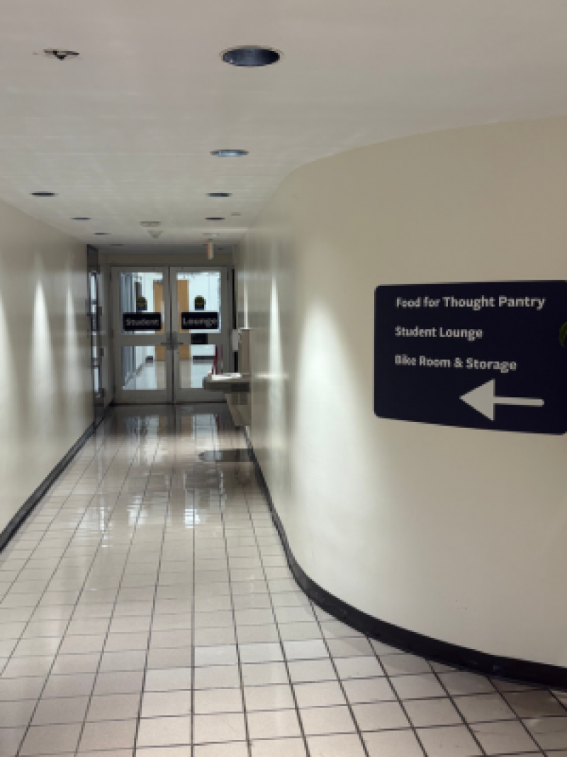 Hallway with tiled floor, curved wall, and a sign pointing left toward pantry and lounge.