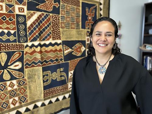 Department of International Health and Sustainable Development | Tulane University School of Public Health and Tropical Medicine Martha Silva standing near a tapestry, smiling