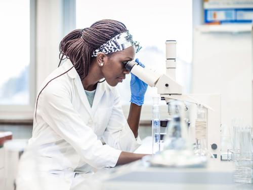 Cancer Concentration | School of Public Health and Tropical Medicine woman looking into micrscope in a lab setting