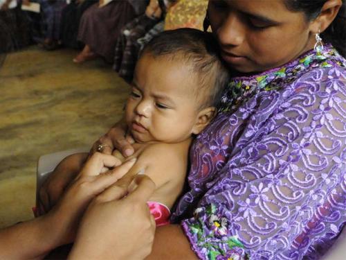 International Health and Sustainable Development zoom button | New Student Orientation mother with infant receiving a vaccination