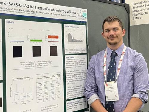 Keegan Brighton, standing next to a poster at a poster session