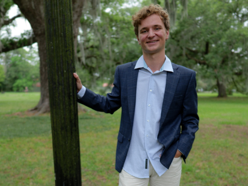 Student Ambassador Liam Guest | Celia Scott Weatherhead School of Public Health and Tropical Medicine Liam Guest leaning on a light pole poutdoors