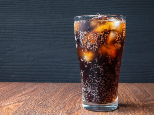 Photo of a glass full of soda and ice on a table