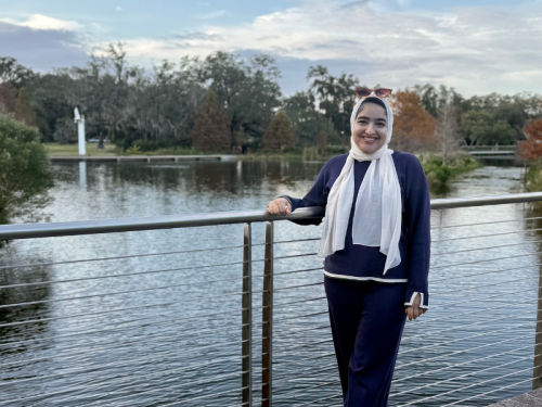 Wafaa Elwakli standing near a body of water, next to a railing, smiling at the camera