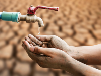 Hands cupped under water drip in drought conditions
