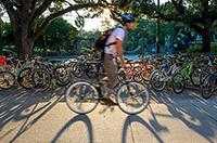 Person riding a bicycle on Tulaen uptown campus, past a row of parked bikes