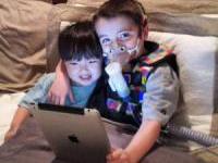 A kid getting asthma treatment and playing on a laptop