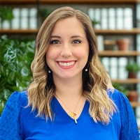MaryCeleste Mendoza headshot, blue shirt, books on a shelf in background