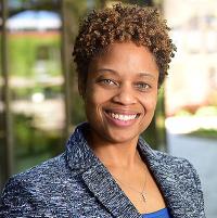 Jeannine Coxen headshot, smiling at camera, golden sunlight in background