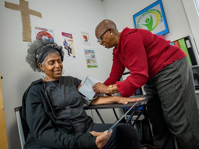 Minister Bettie Rhodes (right) checks a parishioner's blood pressure at Cornerstone United Methodist Church in New Orleans. (Photo by Paula Burch-Celentano)