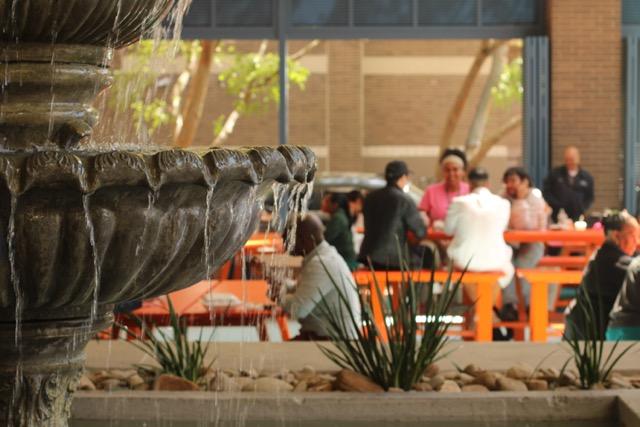 Fountain in foreground, people eating in background at Wave City Market