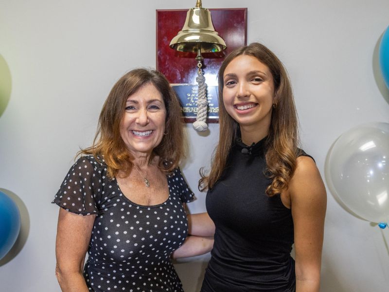 Isabella Spar poses with her mother Wendy Jeshion in front of a bell
