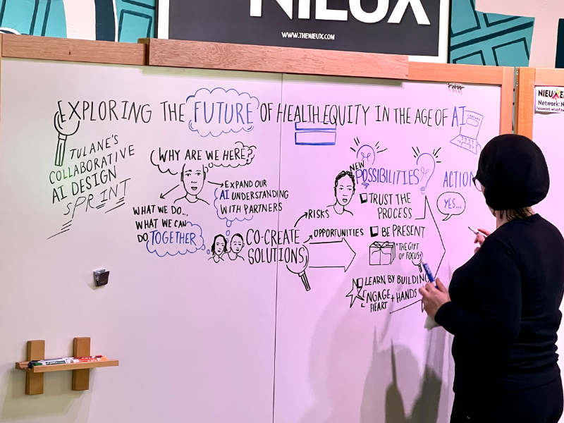 Woman sketching diagrams about health equity and AI on a large whiteboard.