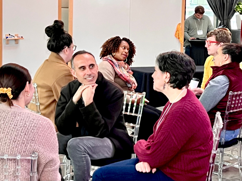 Diverse group of adults actively discussing in a circle during an indoor event.