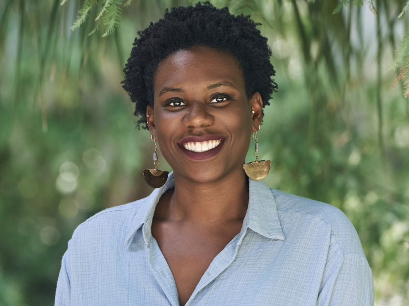 Samantha Fleurinor smiling against blurred green leaves.