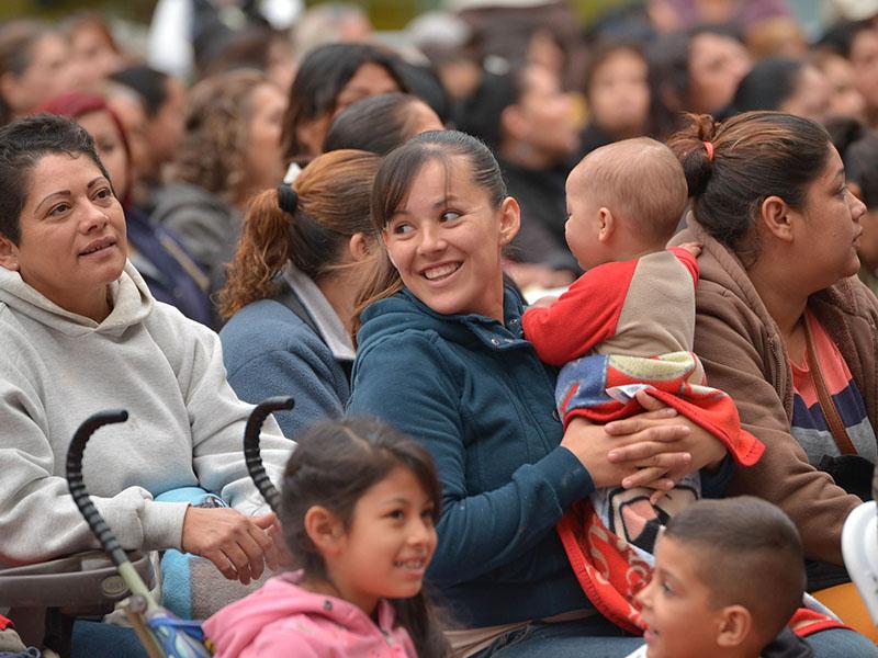 Crowd of people, woman holding a bay. 