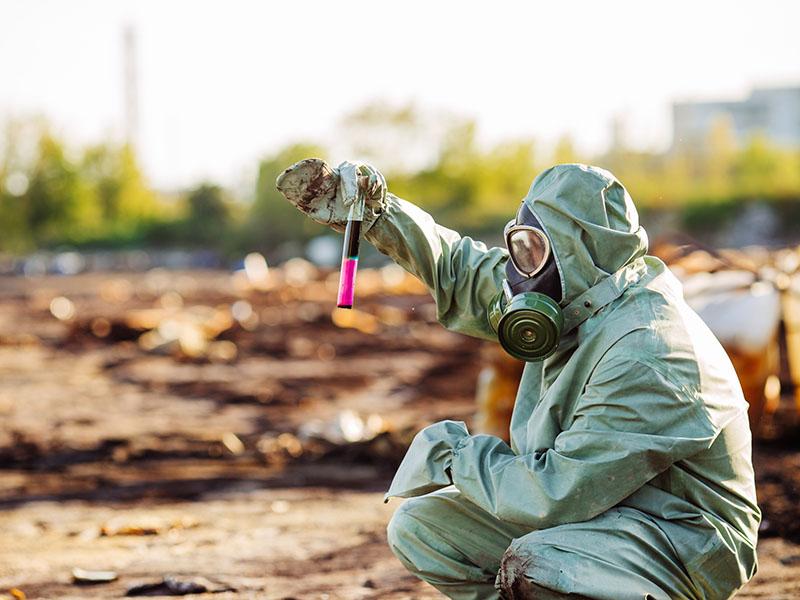 Environmentalist collecting samples, wearing hazmat suit