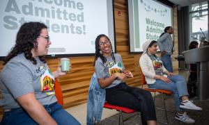 Three smiling young women at a "Welcome Admitted Students" event.